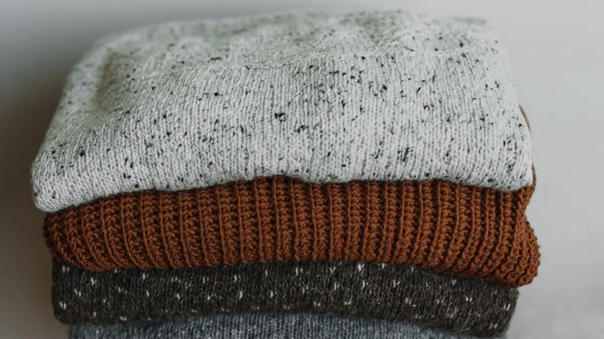 Pile de pulls en laine pliés, de couleurs automnales